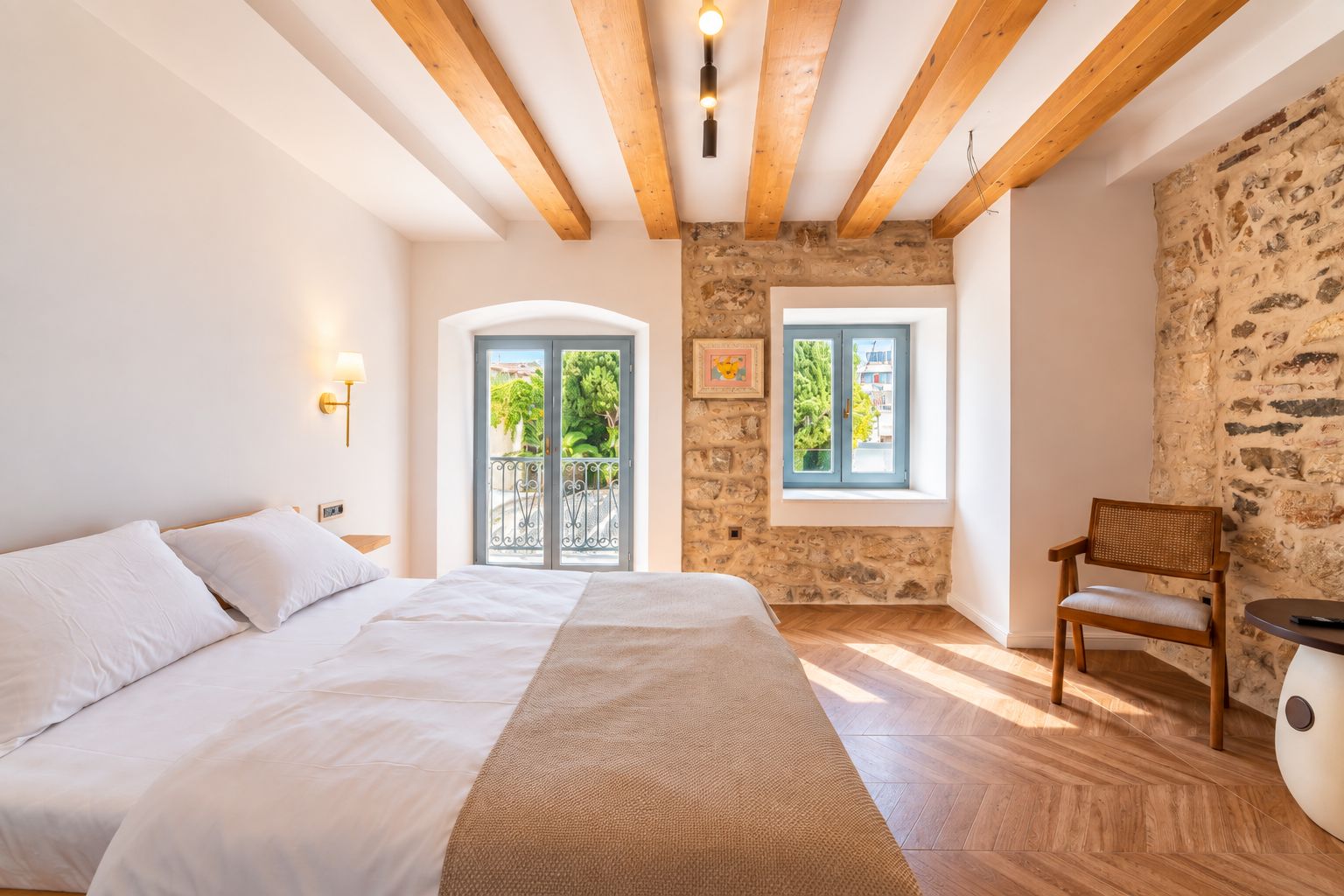 Ein Schlafzimmer mit einem Bett, einem Stuhl, einer Steinwand und einem Fenster.