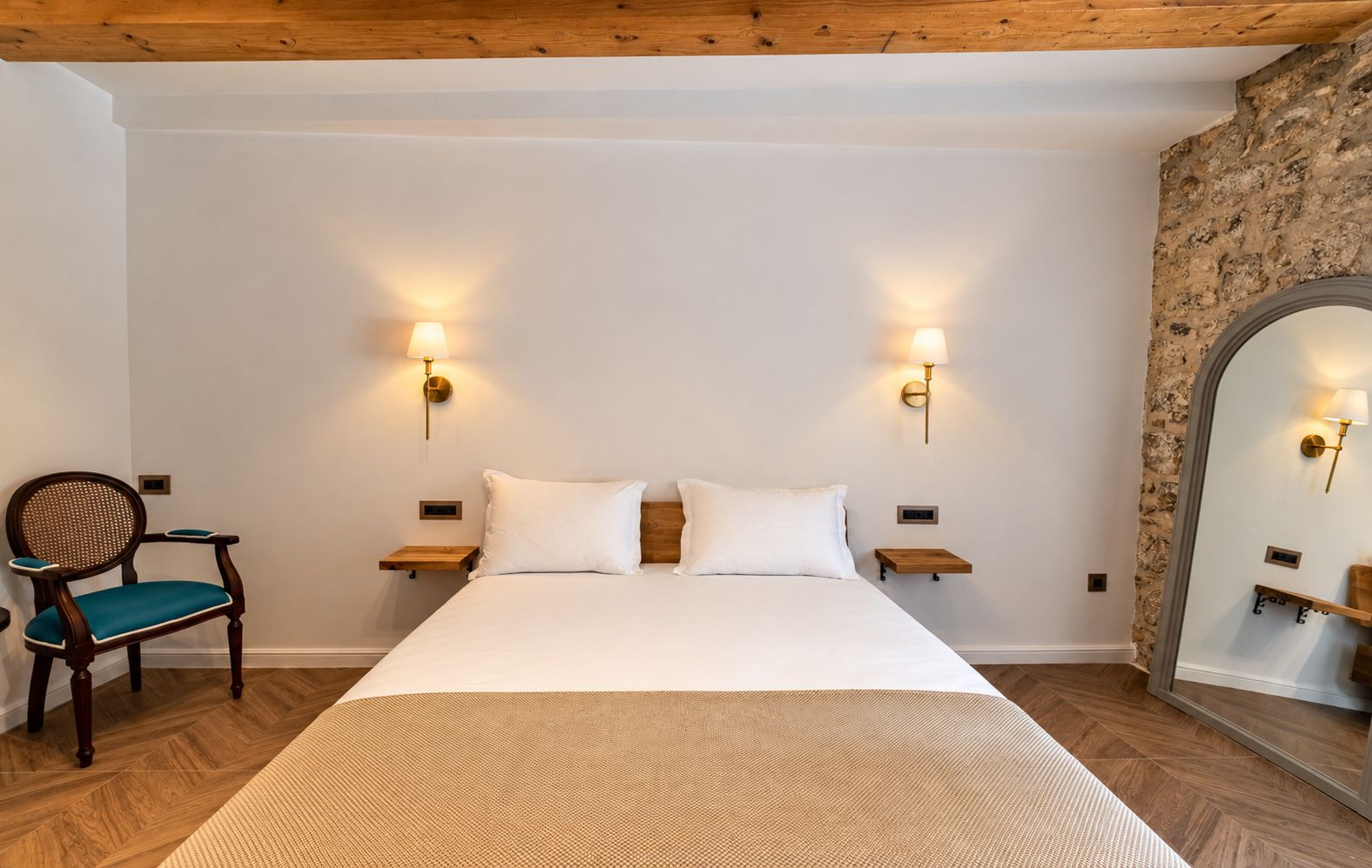Une chambre d’hôtel avec un grand lit, deux tables de chevet, une chaise et un miroir.