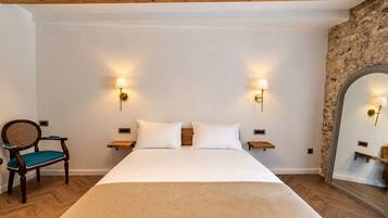 Une chambre d’hôtel avec un grand lit, deux tables de chevet, une chaise et un miroir.