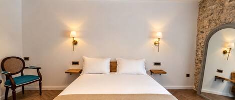 A hotel room with a large bed, two bedside tables, a chair, and a mirror.