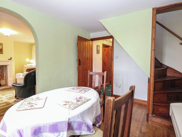 A room with a dining table, chairs, a fireplace, and a staircase.