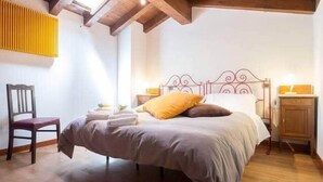 Ein Schlafzimmer mit Bett, Sessel, Nachttisch und Heizkörper.