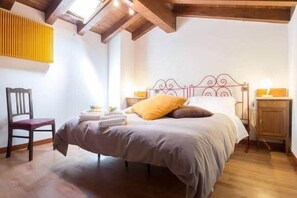 A bedroom with a bed, a chair, a bedside table, and a radiator. - Horizon holiday home (Montecchio)
