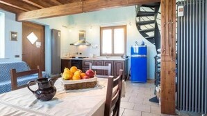 Eine rustikale Küche mit Holzbalken, einem Esstisch mit Früchten und einem blauen Kühlschrank.