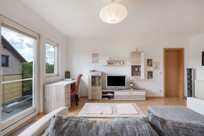 Un salon moderne doté d’un téléviseur, d’un coin salon et d’une grande fenêtre.
