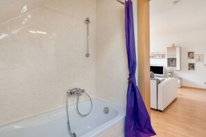Une salle de bain moderne avec une baignoire, une douche et un rideau de douche violet.