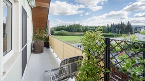 Un balcon donnant sur un paysage verdoyant et sur un passage à niveau.