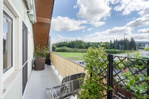 Een balkon met uitzicht op een groen landschap en een spoorwegovergang.