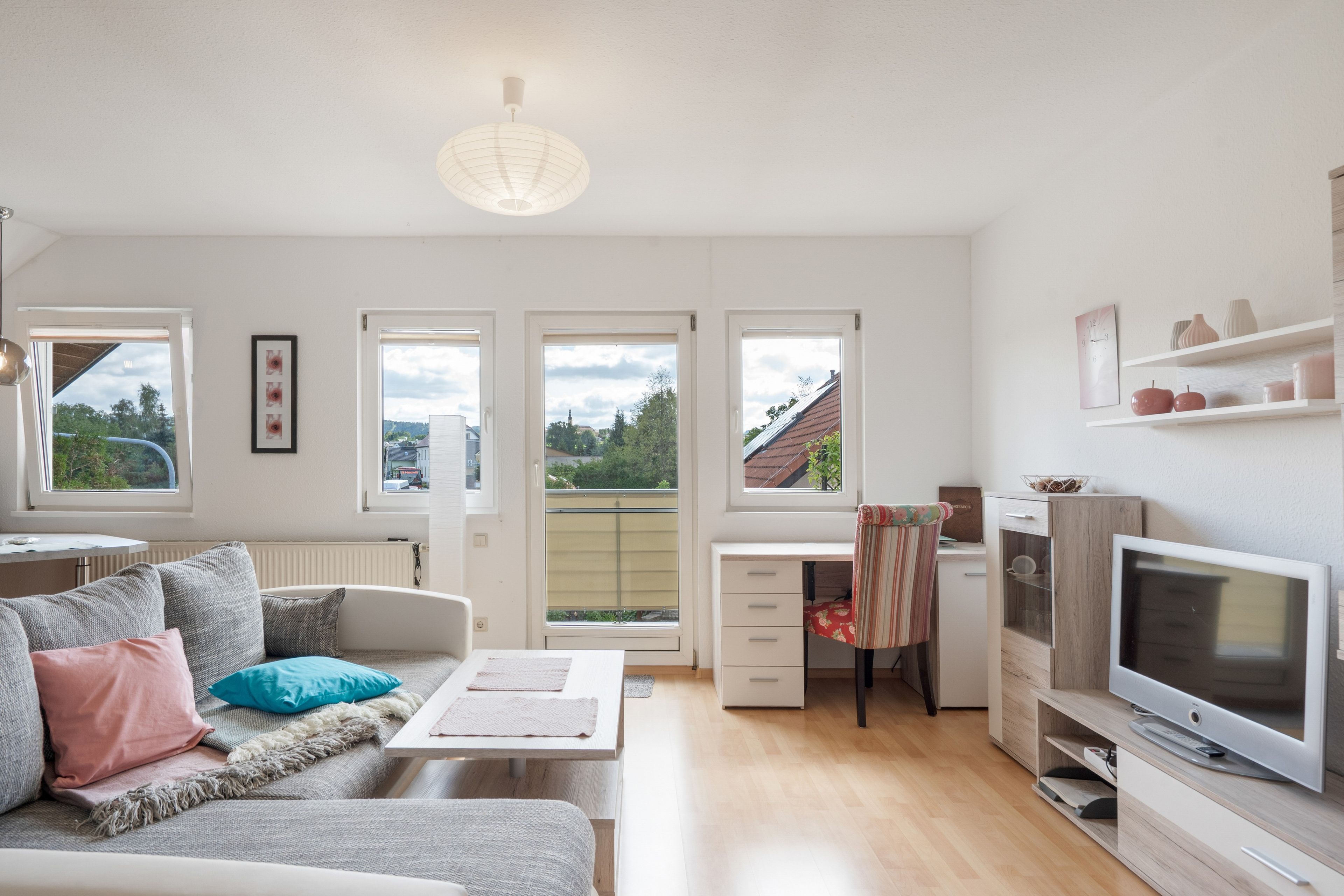 Ein modernes Wohnzimmer mit einer Couch, einem Esstisch, einem Fernseher und einem Schreibtisch.