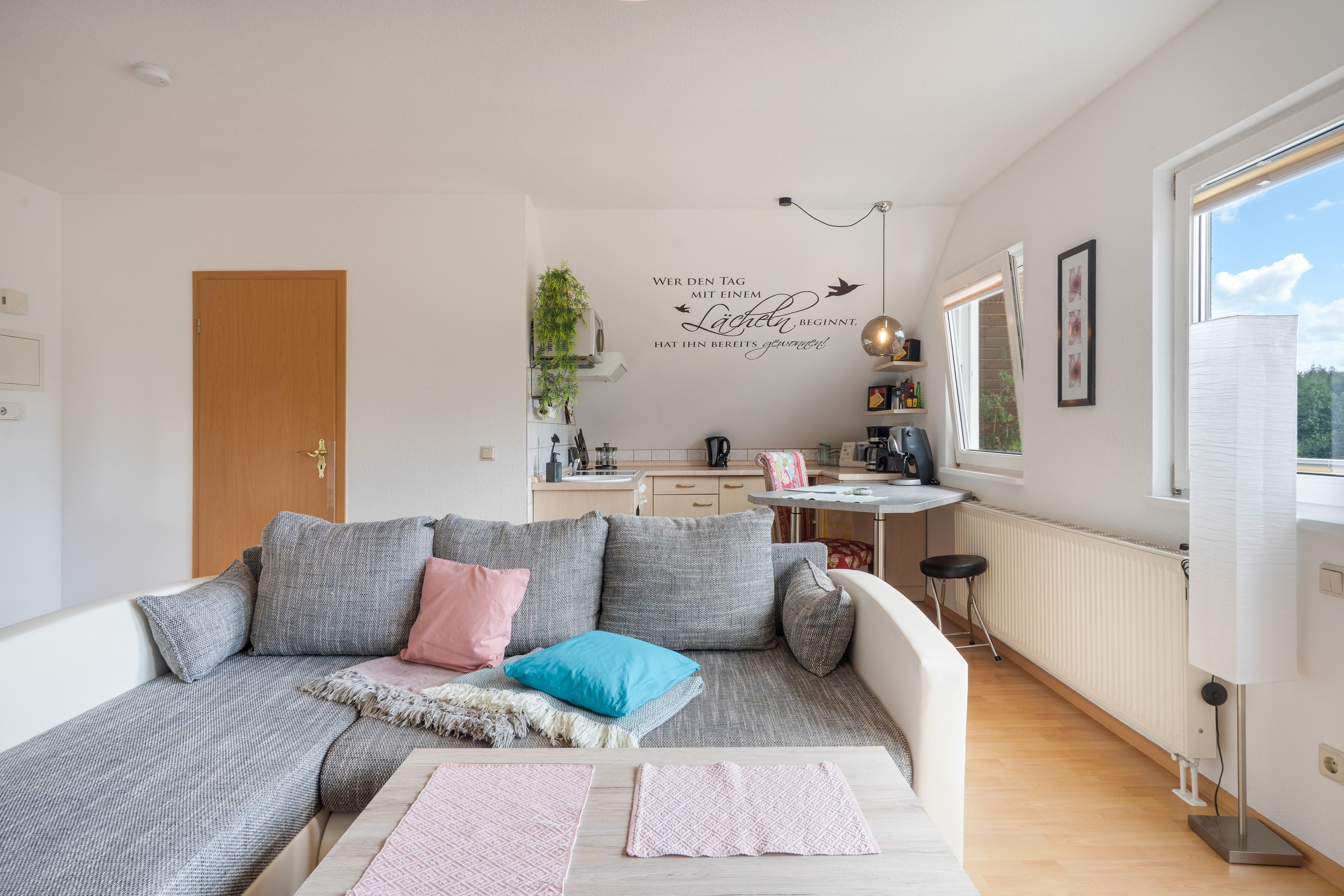 Un salon moderne avec un canapé, une table basse et un coin cuisine à l’arrière-plan.