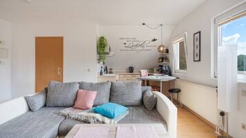 Un salon moderne avec un canapé, une table basse et un coin cuisine à l’arrière-plan.