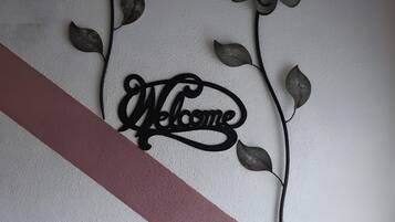 A wall with a decorative metal sign that reads 'Welcome' and two stylized flowers.