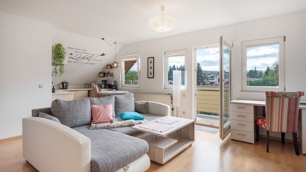 Un salon moderne avec un canapé, une table basse et une vue sur l’extérieur grâce à une porte vitrée.