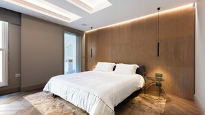 A modern bedroom with a large bed, a small side table, and a unique wooden wall design. - LuxTOPFloor (Valletta)