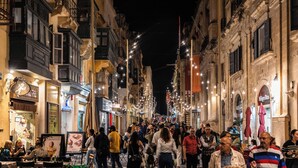 A crowded street at night with illuminated buildings and people walking. - LuxTOPFloor (Valletta)