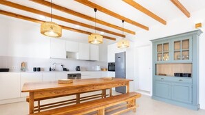 Una cocina moderna con vigas de madera, una gran mesa de madera y un armario azul.