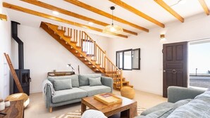 Una sala de estar moderna con una escalera, un sofá, una mesa de centro y una chimenea.