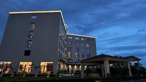Egy modern stílusú, többemeletes szálloda, melynek nagyméretű, üvegportálos bejárata és fedett, szabadtéri területe van.