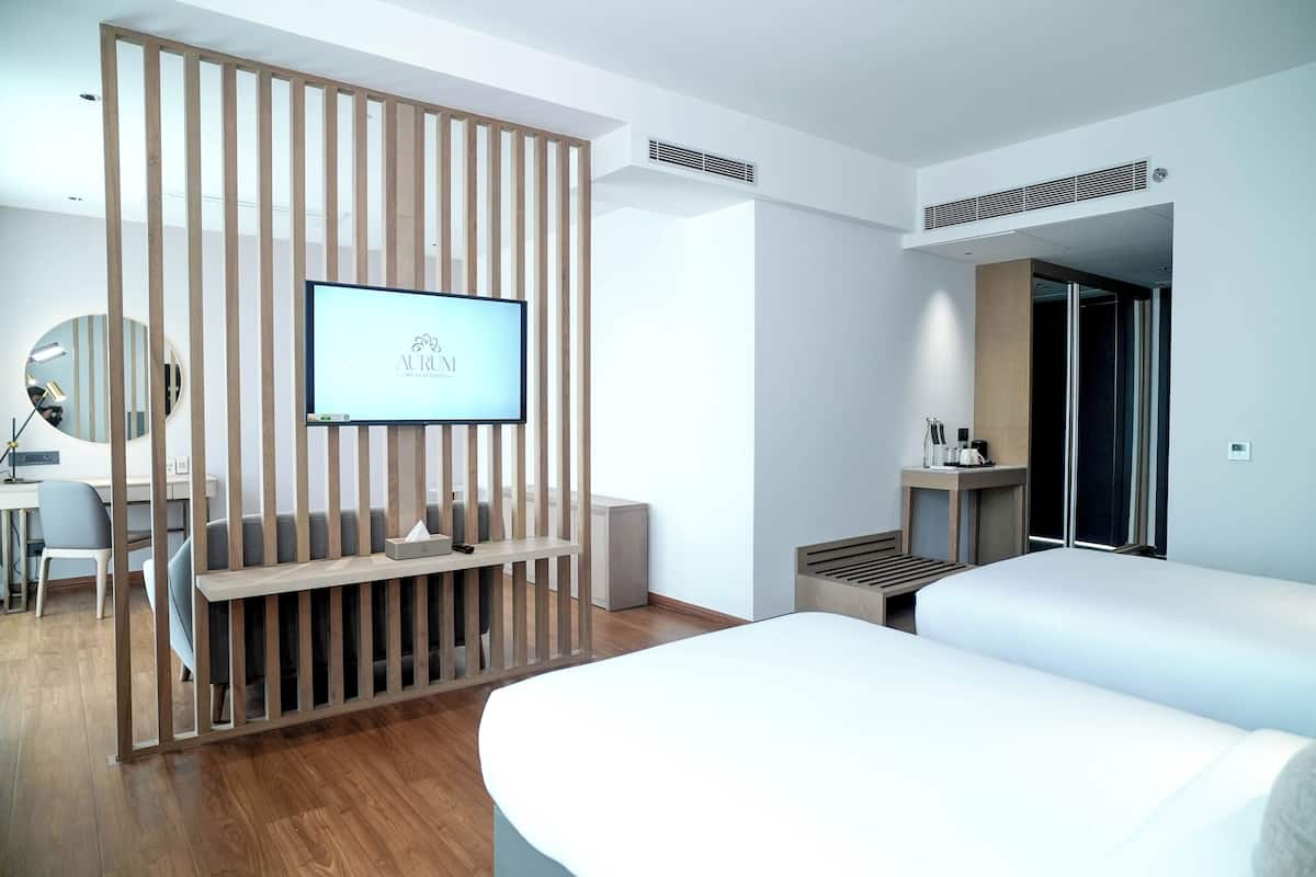 A modern hotel room with a TV, a desk, a chair, a bed, and a wardrobe.