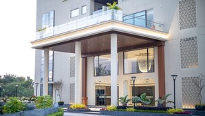 Un hôtel moderne doté d’une entrée abritée, de grandes fenêtres et d’un balcon.