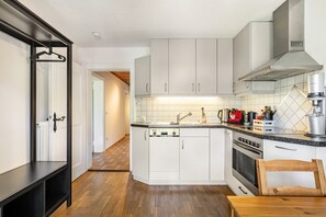 Una cucina moderna con mobili bianchi, forno integrato e macchina da caffè.