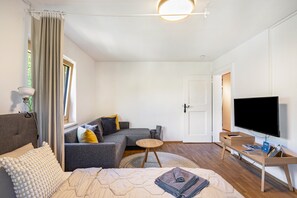 A modern living room with a sofa, a bed, a TV, and a small table. - Tostner Burgblick Apartment – Quiet Green Setting with Balcony (Feldkirch)