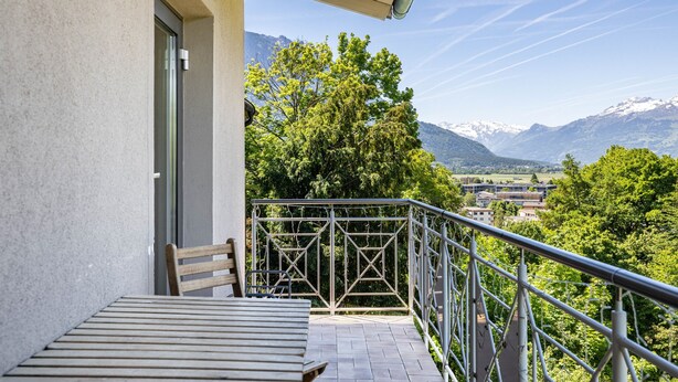 Un balcon avec vue sur les montagnes, une chaise et une table.