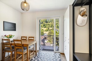 Ein Essbereich mit einem Holztisch und Stühlen, einer Hängelampe und Blick durch eine Glastür auf einen Balkon.