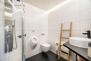 Ein modernes Badezimmer mit einer Glaskabine zur Dusche, einer Toilette und einem Waschbecken mit einer hölzernen Sprosse.