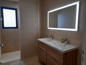 Une salle de bain avec deux lavabos, un miroir et une fenêtre.