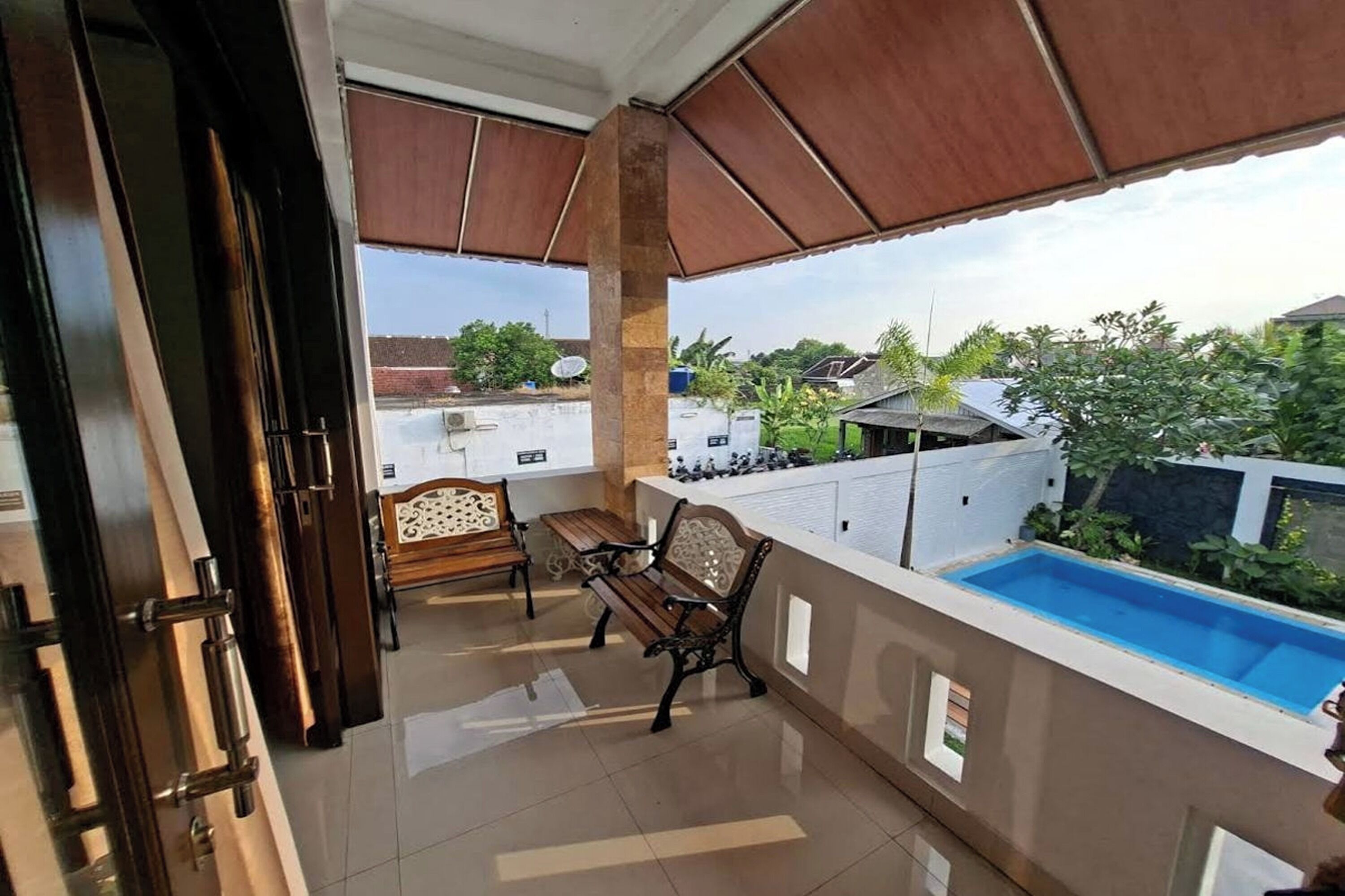 Un balcon avec une piscine, des meubles en bois et une vue sur le quartier.
