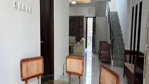 A dining area with a glass-top round table and wooden chairs.