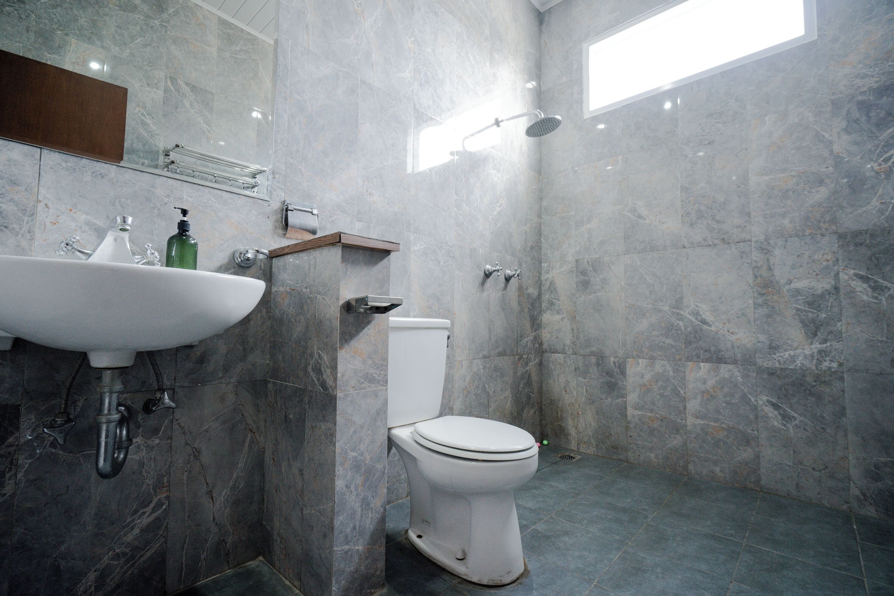 Une salle de bain avec des toilettes blanches, un lavabo et une douche.