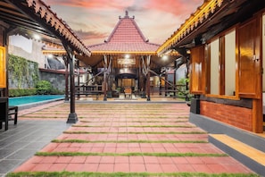 A traditional building with a tiled roof, a central open space, and a pool.