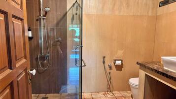 A bathroom with a glass shower enclosure, a toilet, and a sink with a marble countertop.
