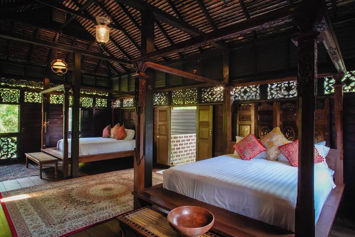 Una habitación tradicional de madera con cama con dosel, un banco y una mesa con un cuenco.