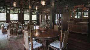 A traditional wooden dining area with a round table, wicker chairs, and a large mirror above the table.