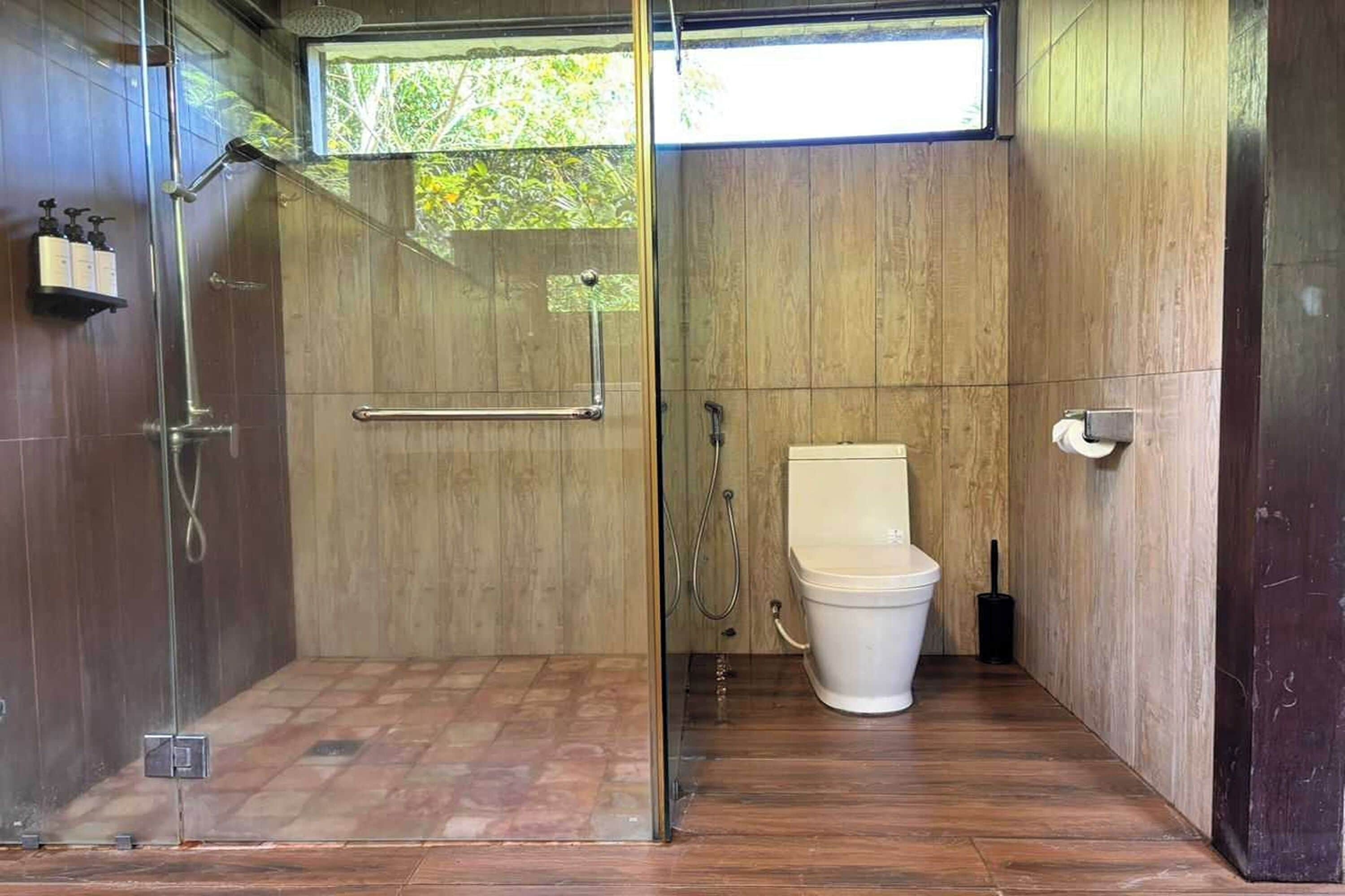 Une salle de bain moderne avec une douche à parois de verre, des toilettes et un lambris en bois.