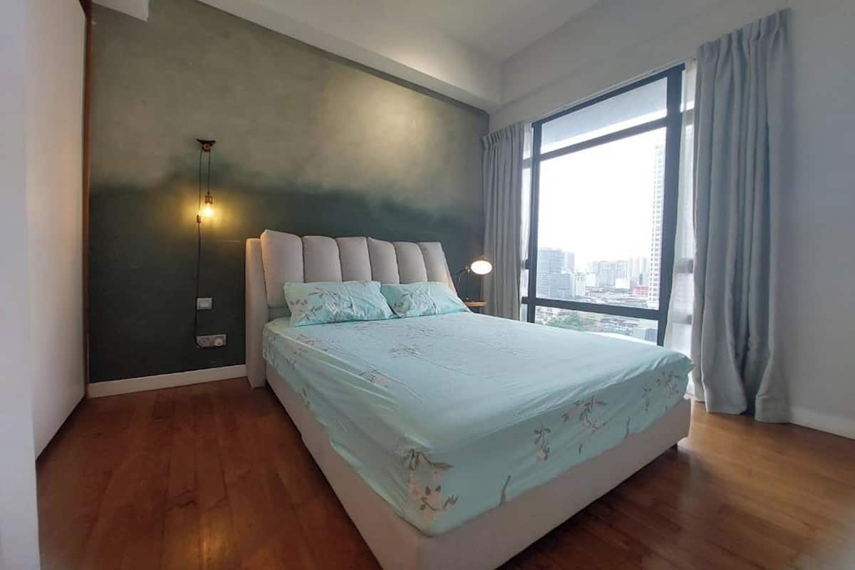 Une chambre avec un lit, une vue sur la ville, une grande fenêtre et un luminaire fixé au mur.