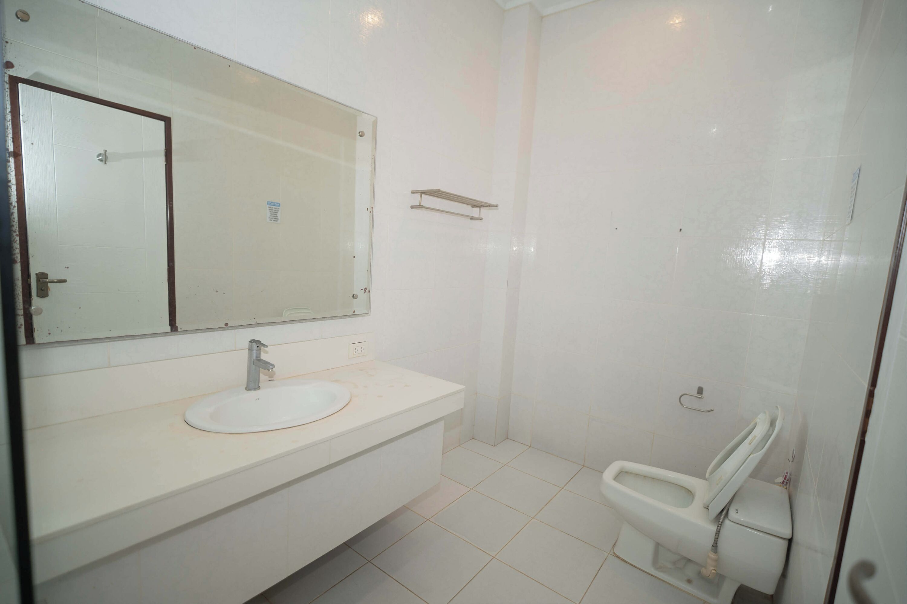 Un baño con lavamanos, espejo y retrete blancos.
