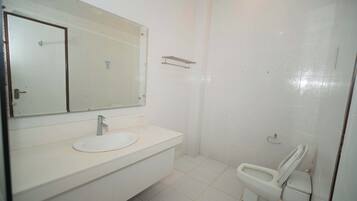 Un baño con lavamanos, espejo y retrete blancos.