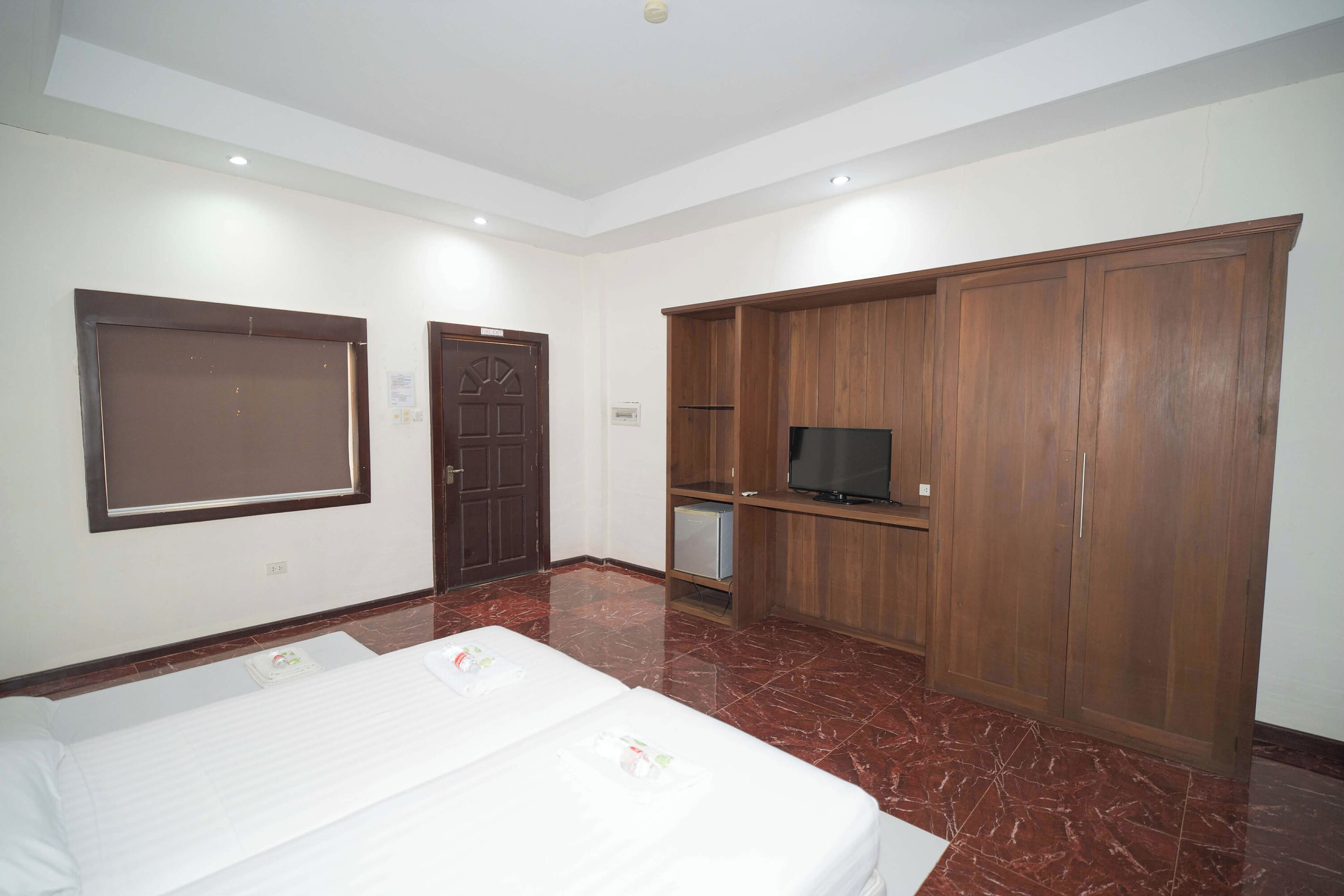 A hotel room with a bed, wardrobe, television, and a door.