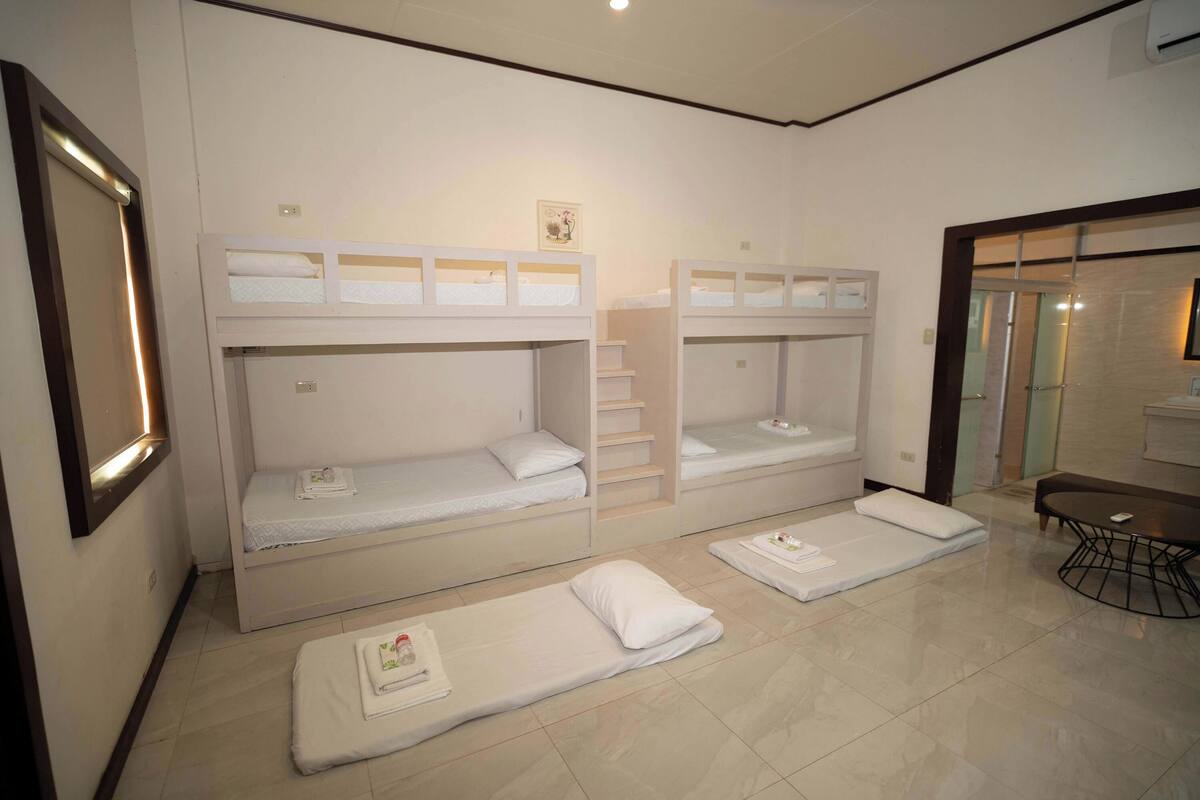 A hotel room with bunk beds, a small table, and a mirror.