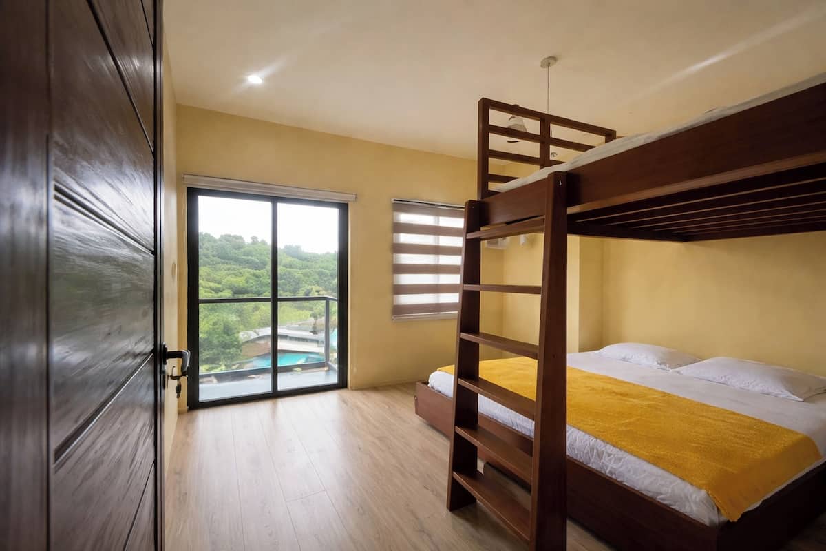 Una habitación con literas, un ventanal corredero que da a un balcón y vistas a zonas verdes.