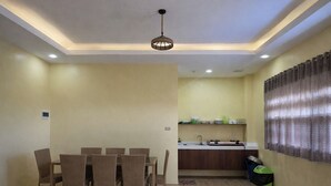 A dining area with a table and chairs, a kitchen with a sink, and a ceiling light fixture. - Lisro Sleep And Relax La Union near Beach (San Juan)