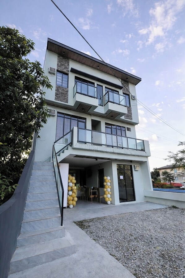 A multi-story building with a balcony, a staircase, and a small outdoor seating area.
