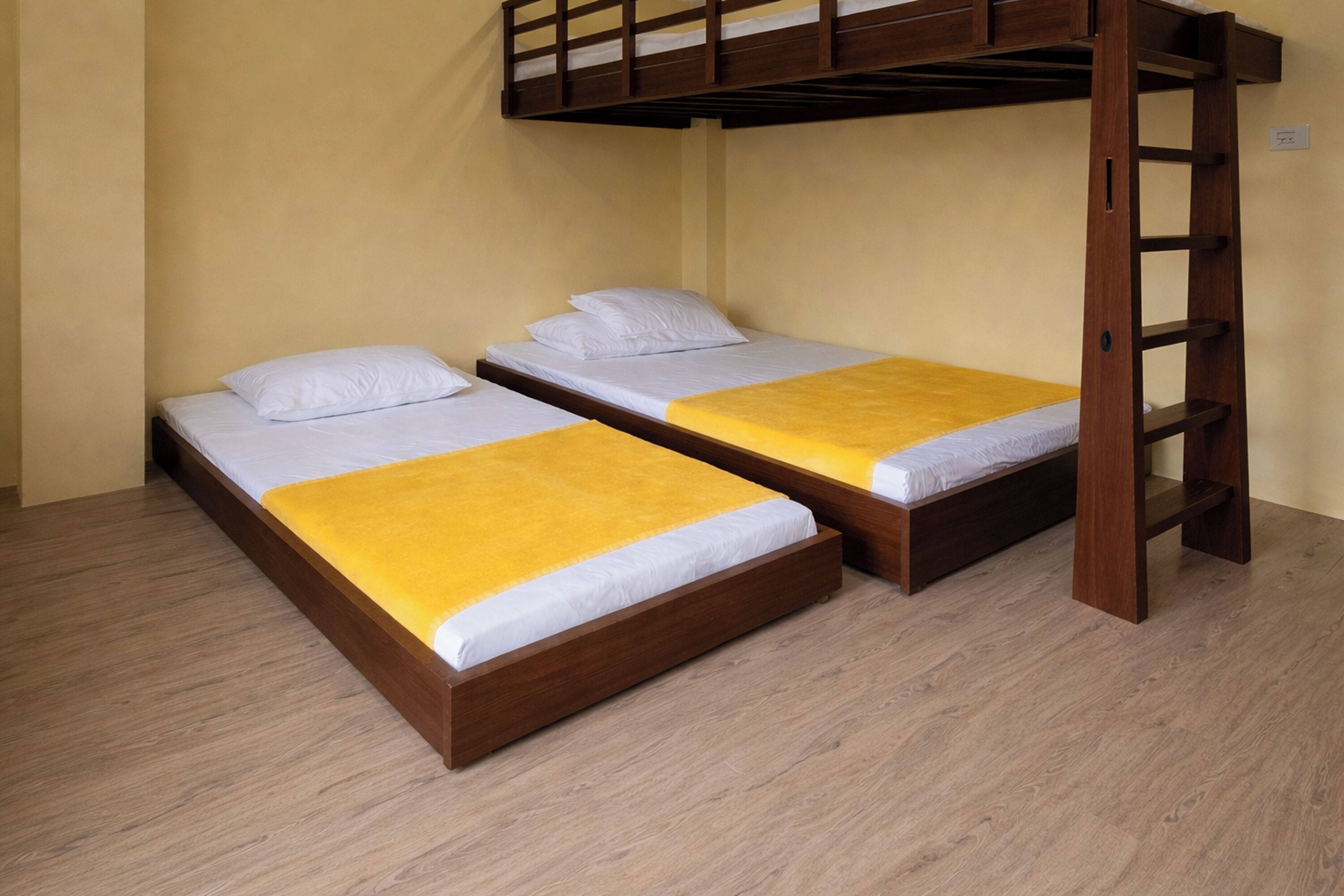 Quarto com duas beliches de madeira, uma escada de madeira e piso em tom claro.