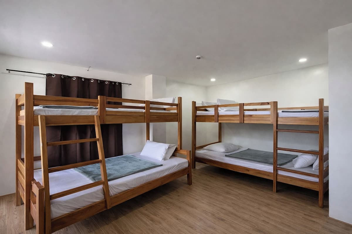 Una habitación con literas, suelo de madera y una cortina.