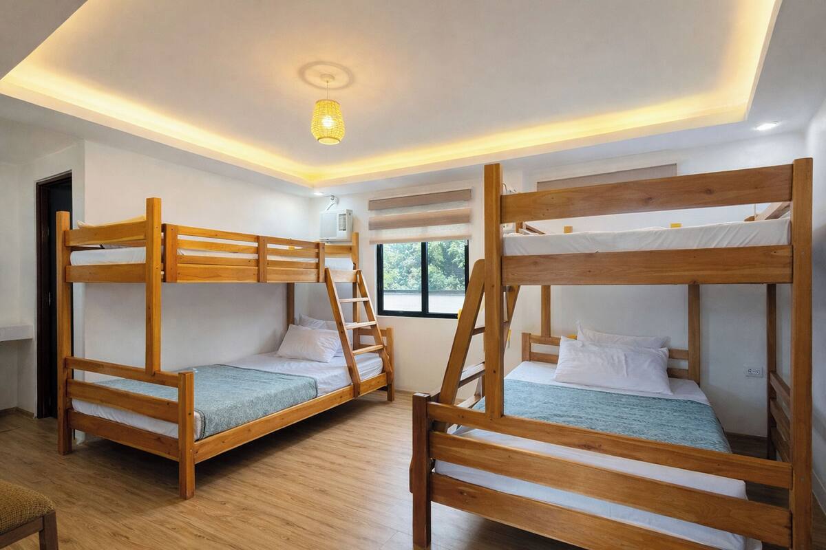 Una habitación con literas, una lámpara en el techo y una ventana.