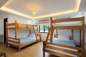 Ein Zimmer mit Etagenbetten, einer Deckenlampe und einem Fenster.